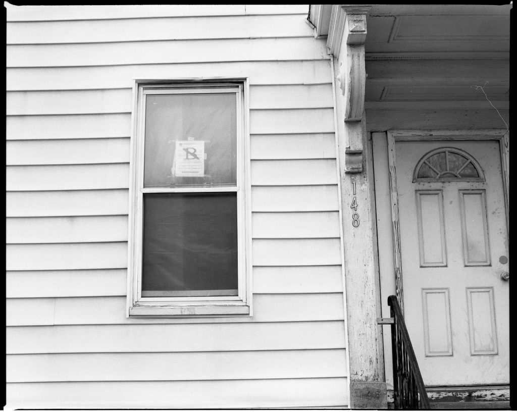 A black and white photo of a house with a door.